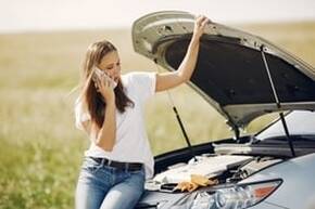 A young lady has a broken down car. 