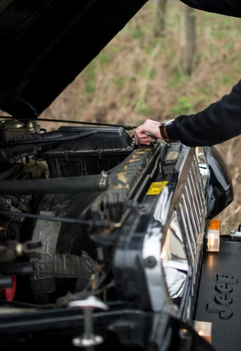 A jeep has its hood up from an unwanted breakdown